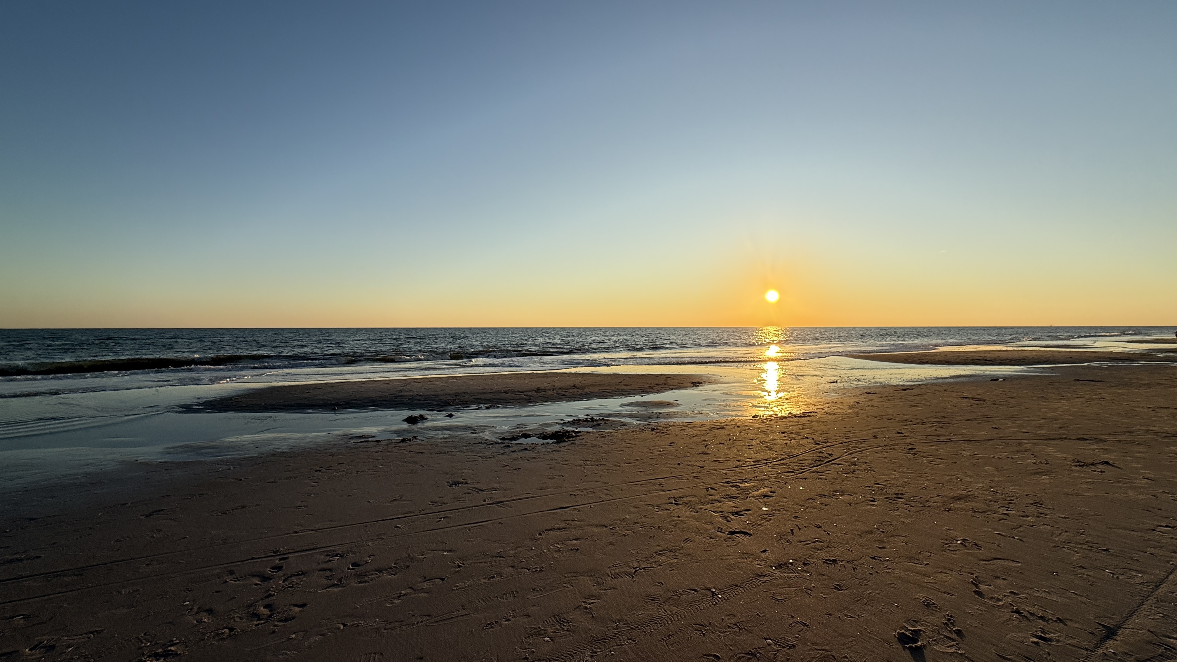 Quiet Oak Island beach at golden hour with tidal pool reflections