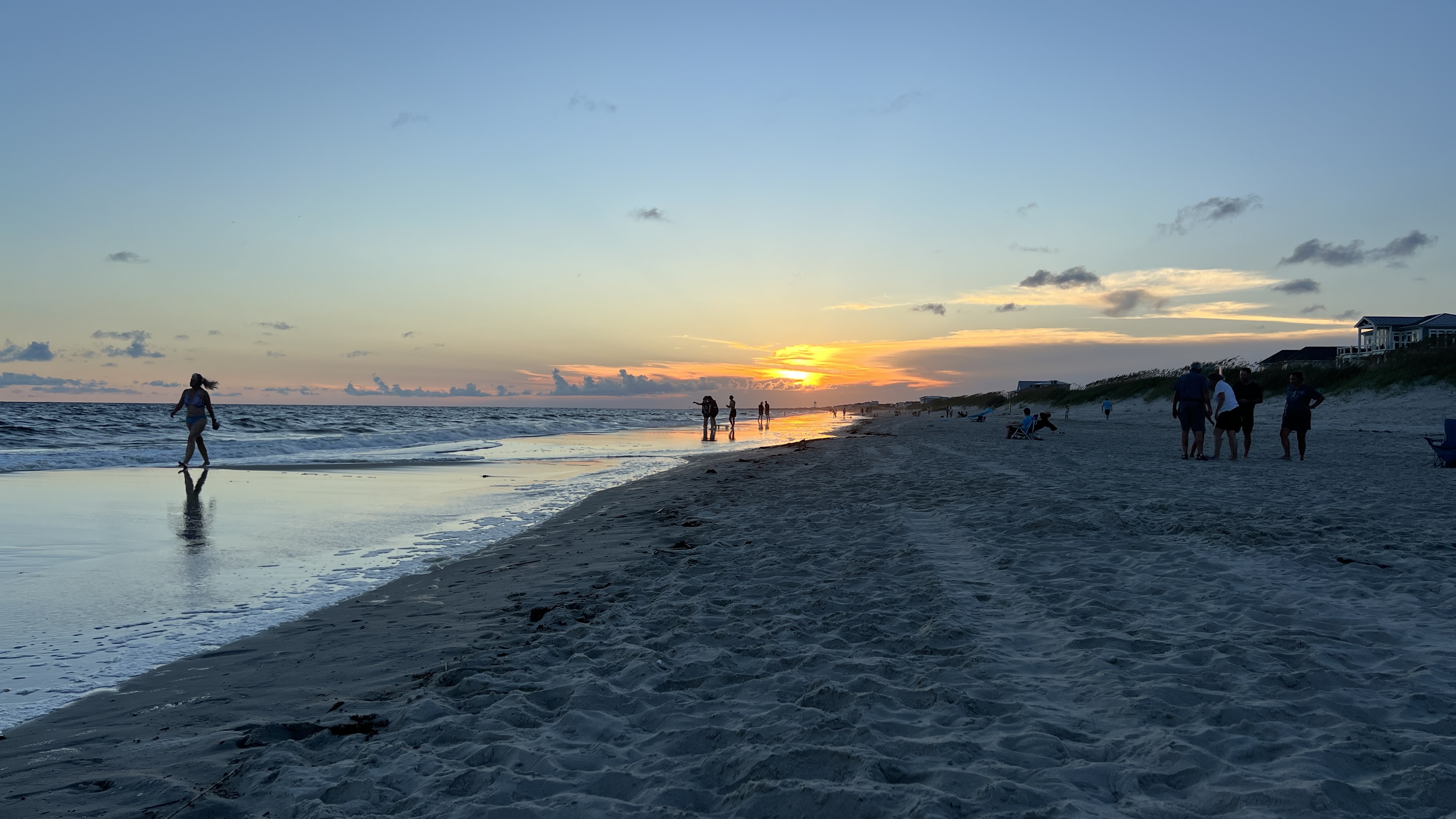 Families walking the Oak Island shoreline at sunset